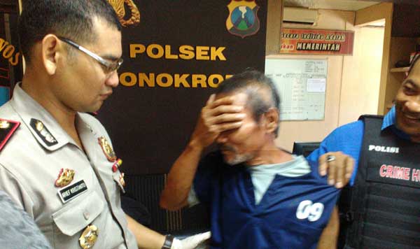 Tersangka Yudi yang menghamili cucunya didampingi Kapolsek Wonokromo. foto: ekoyono/ BANGSAONLINE