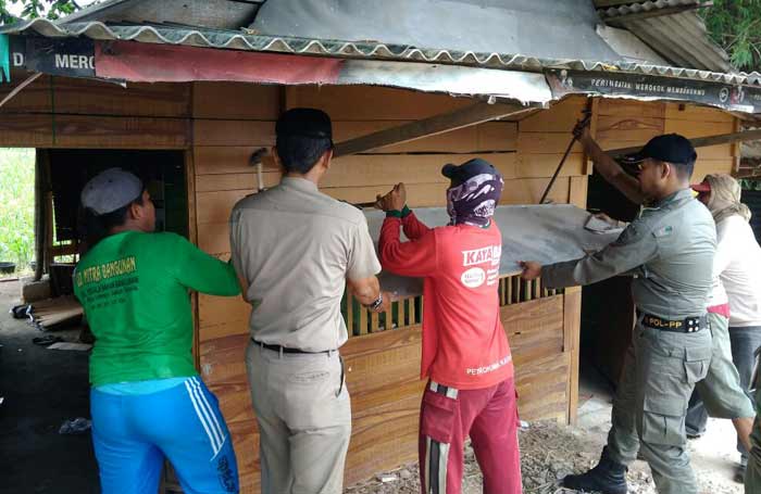 Petugas Dispol PP dibantu Muspika Dukun saat membongkar salah satu warung remang-remang.