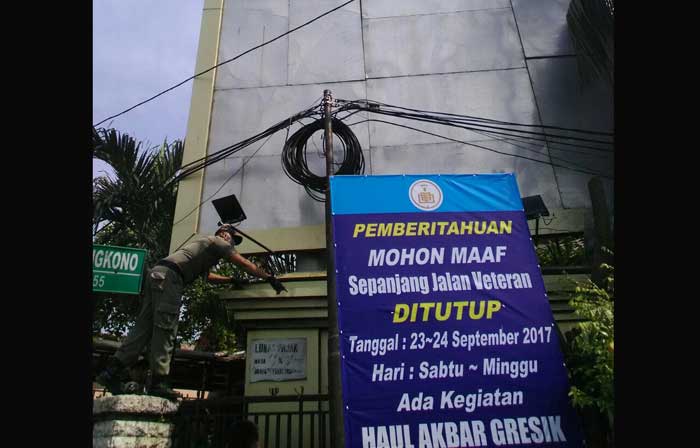 Petugas Dispol PP Pemkab Gresik saat hendak menurunkan salah satu reklame yang diketahui ilegal. foto: SYUHUD/ BANGSAONLINE