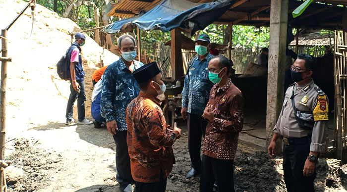 Camat Kedamean, Sukardi (dua dari kanan), membelakangi kuburan sapi seberat 1,2 ton yang mati terserang PMK milik peternak di Desa Sidoraharjo. Foto: SYUHUD/BANGSAONLINE