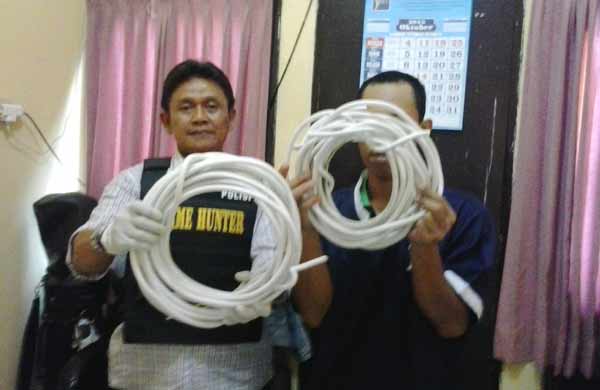 Tersangka (kanan) didampingi petugas saat menunjukkan barang bukti berupa gulungan kabel. foto: rusmiyanto/BANGSAONLINE