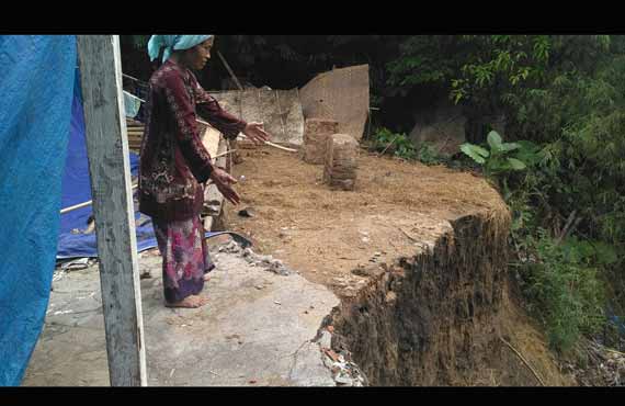 Mahrusah menunjukkan bibir sungai yang semakin mendekati rumahnya. foto: AHMAD/ BANGSAONLINE