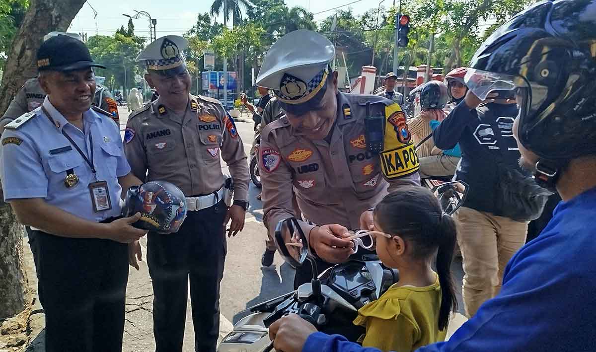 Petugas saat membagikan helm ke pengendara dalam Operasi Patuh Semeru 2025 di Jombang.