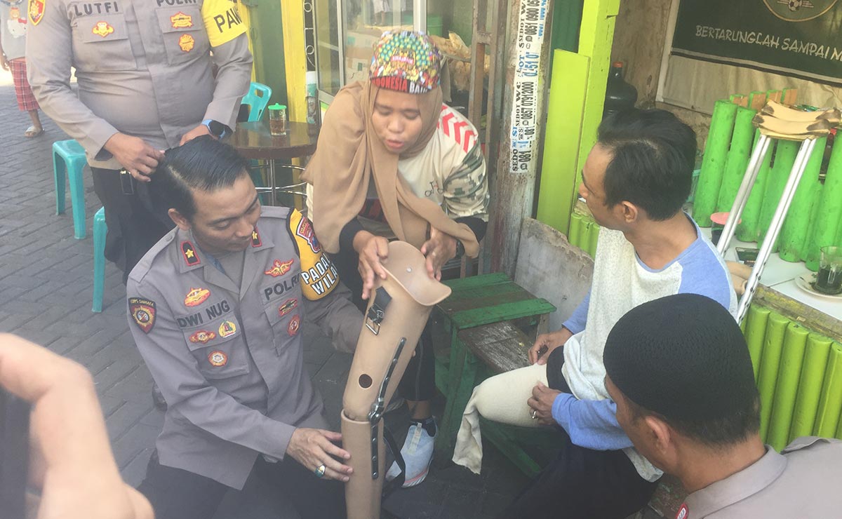 Kapolsek Simokerto Kompol Dwi Nugroho saat memasangkan kaki palsu kepada salah satu penyandang disabilitas.