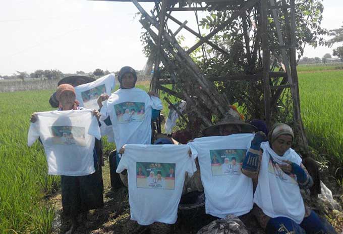 Para petani perempuan menunjukkan kaos Khofifah-Emil. foto: SYUHUD/ BANGSAONLINE