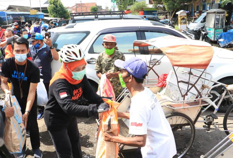 Gubernur Jawa Timur Khofifah Indar Parawansa saat membagikan sembako pada para tukang becak di Jember,  Minggu (15/11/2020). foto: ist/ bangsaonline.com  