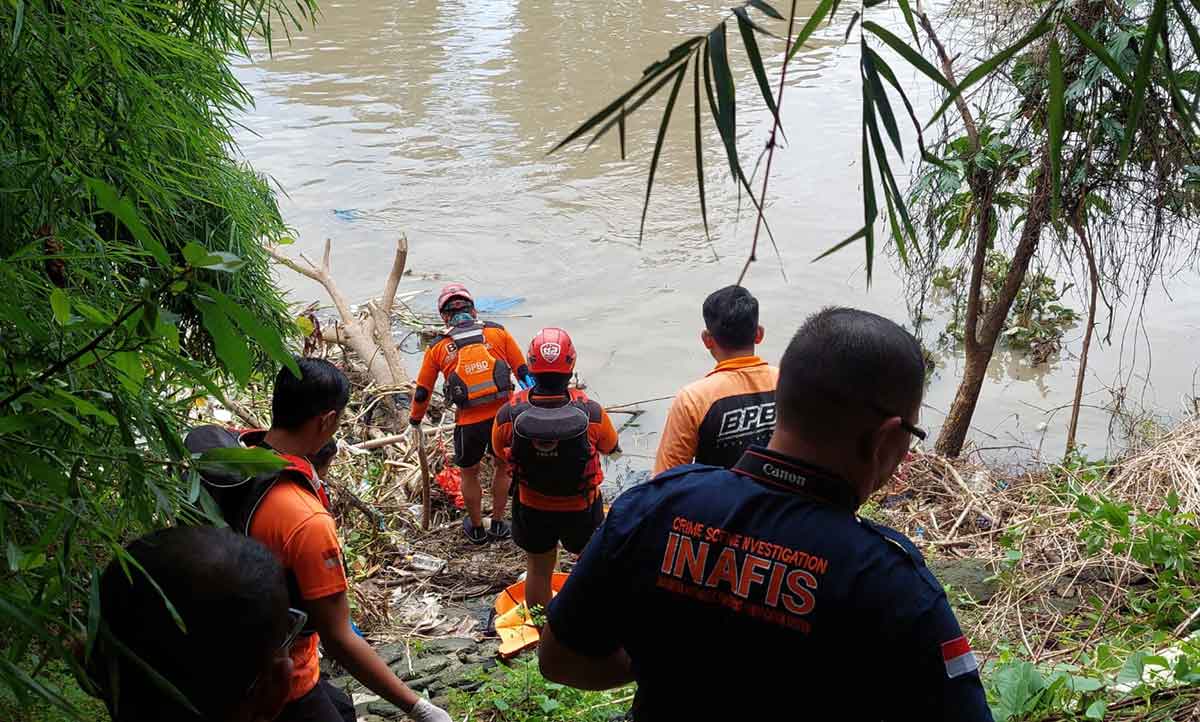 Petugas saat mengevakuasi jenazah perempuan yang mengapung di Sungai Jagir, Surabaya.