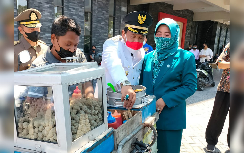 Plt. Bupati Marhaen Jumadi saat memborong dagangan pentol saat mengunjungi para pedagang yang mangkal di Gor Bung Karno. foto: BAMBANG/ BANGSAONLINE