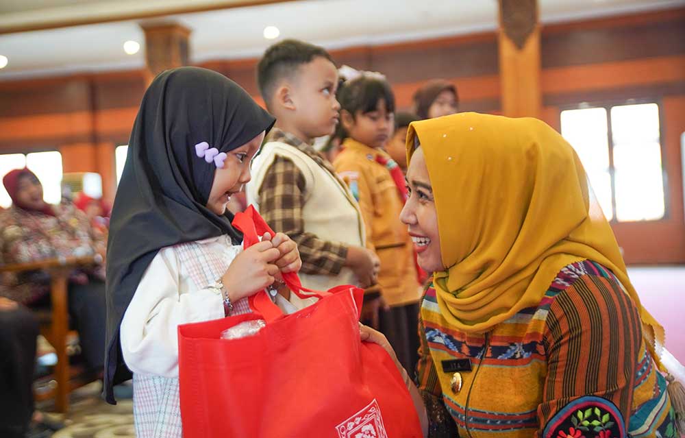 Wali Kota Mojokerto Ika Puspitasari menyapa salah satu siswi yang mendapat bantuan seragam dan peralatan sekolah gratis.