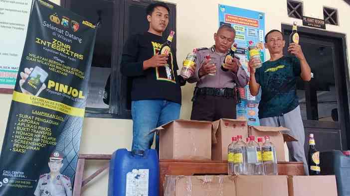 Petugas Polsek Wates saat menunjukkan barang bukti berupa 77 botol miras dan 2 jirigen arak. Foto: Ist.