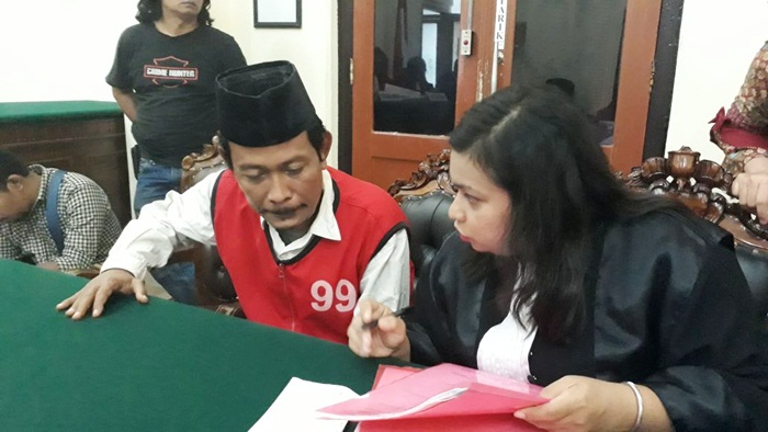 Terdakwa saat berdiskusi dengan kuasa hukumnya.
