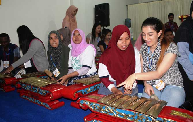 Mahasiswa asal mancanegara ini sedang menjajal alat musik gamelan.