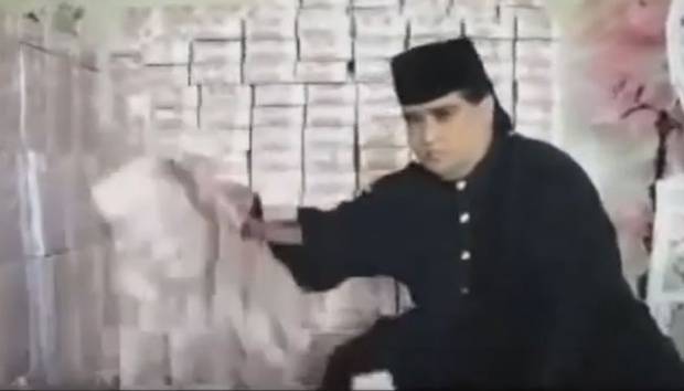 Dimas Kanjeng Taat Pribadi bersama tumpukan uang. Foto: youtube.com