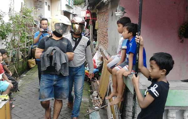 Tersangka Rudi ketika dikeler petugas Polsek Gresik Kota. foto: SYUHUD/ BANGSAONLINE