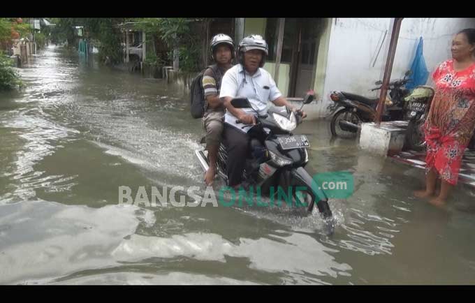 Warga melintasi jalanan yang masih terendam banjir di Desa Rejoagung, Kecamatan Ploso, Kabupaten Jombang, Jumat (13/1). foto: RONY S/ BANGSAONLINE