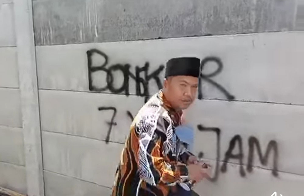 Anggota DPRD Kabupaten Malang, Zia Ulhaq, saat menuliskan tanda pembongkaran tembok.