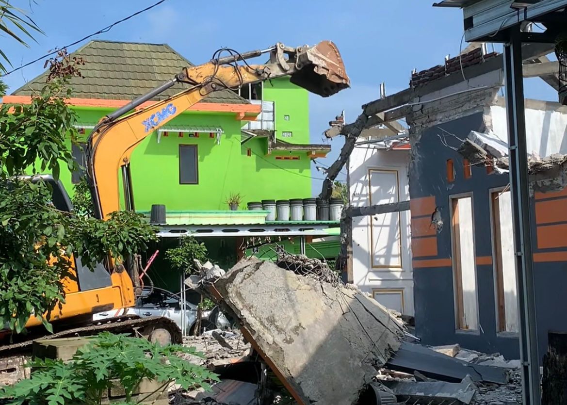 Proses pembongkaran rumah menggunakan ekskavator