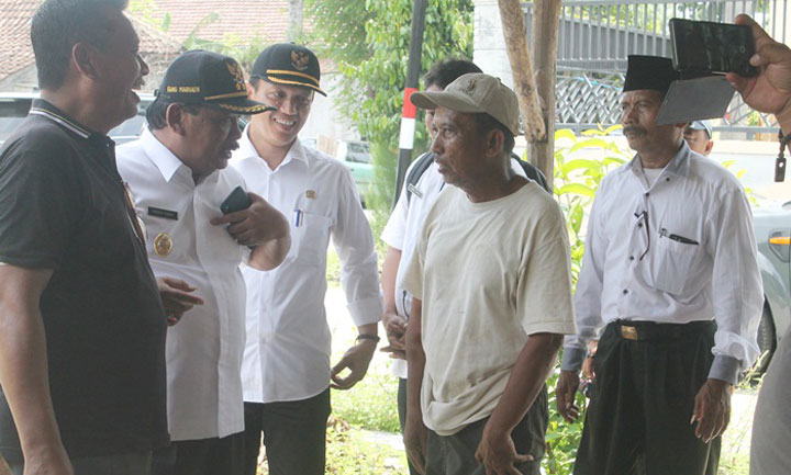 Wabup Kang Marhaen saat berbicara dengan Tukinah yang sebagian rumahnya ikut dibongkar. foto: BAMBANG/ BANGSAONLINE