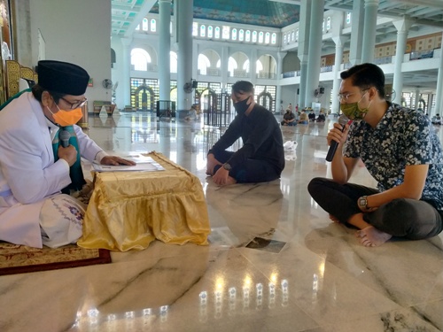Yoki Dwi Yuswanto (kiri) dan Argo Ami Arfiramantyo Daud (kanan pegang mik) saat mengikrarkan dua kalimat syahadat di depan Dr KK M Sujak, Kepala Badan Pengelola Masjid Nasional Al-Akbar Surabaya, Jumat (26/6/2020). foto: MMA/ BANGSAONLINE.COM
