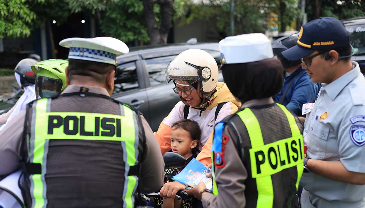 Petugas dari Satlantas Polres Gresik saat menyosialisasikan keselamatan berkendara kepada pengguna jalan sembari membagikan cokelat. Foto: Ist
