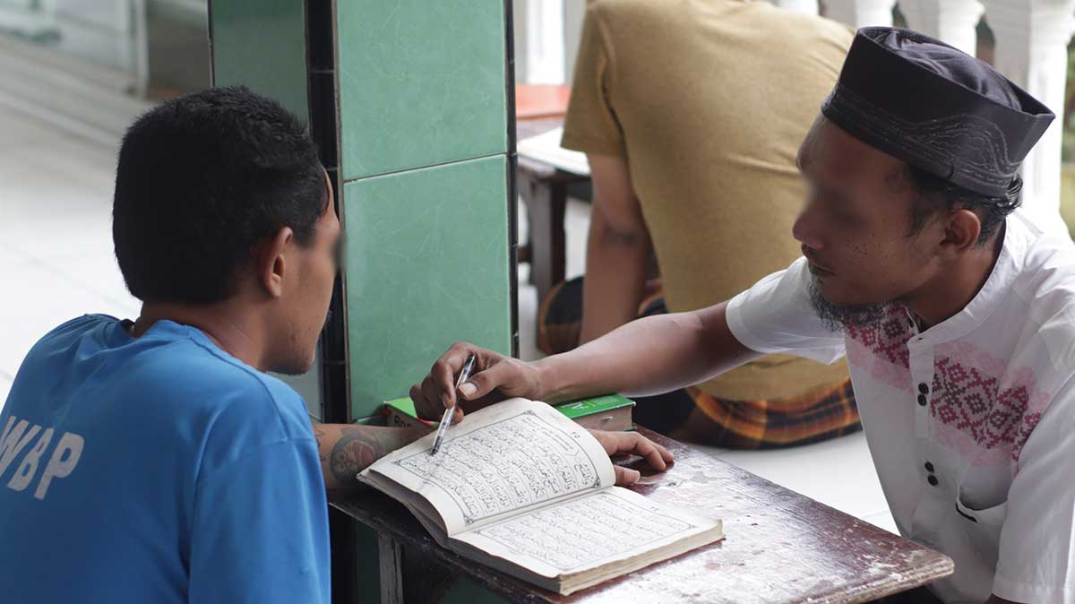Salah satu warga binaan Lapas Kediri saat belajar membaca Alquran. Foto: Ist