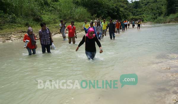 TURUN LANGSUNG: Anggota Komisi V DPR RI, Hj. Sadarestuwati (depan) saat menyebrangi satu dari tiga sungai untuk menuju SDN Pojok Klitih 3 Plandaan.