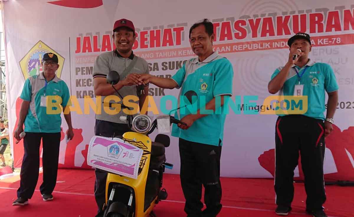 Kades Sukomulyo, Subiyanto, saat menyerahkan hadiah utama motor listrik kepada pemenang. Foto: SYUHUD/BANGSAONLINE
