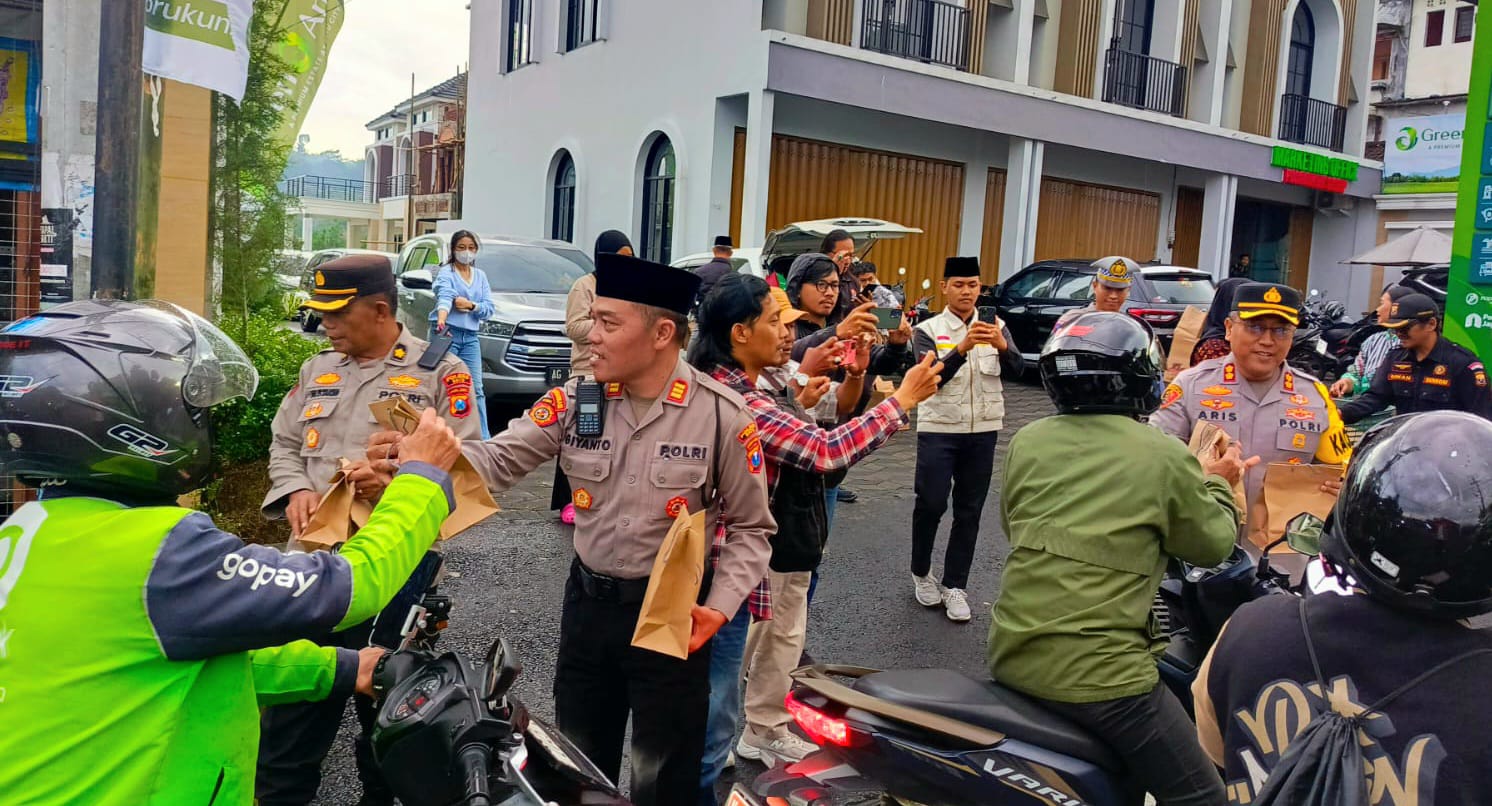 Sejumlah pengendara yang melintas saat menerima bingkisan takjil dari anggota Polres Batu