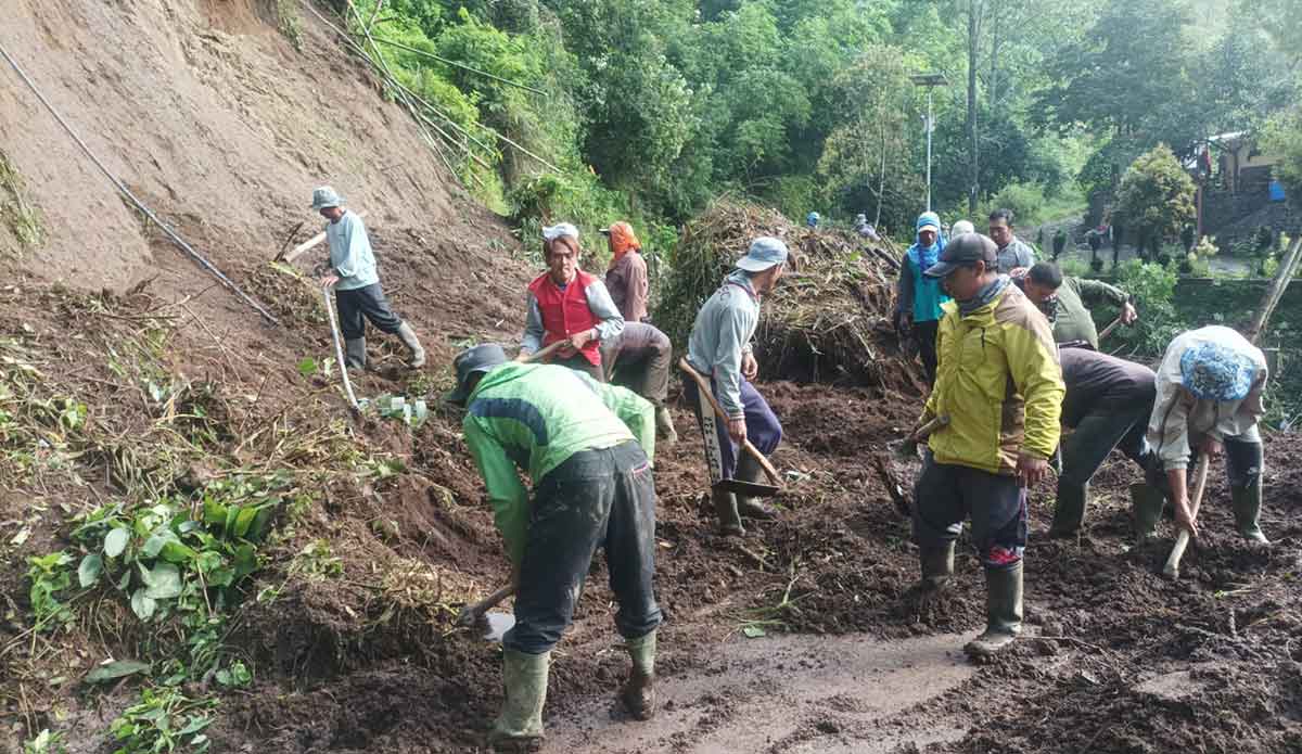 Petugas dari BPBD Kota Batu bersama masyarakat saat berjibaku membersihkan bekas longsor di jalan Pura Giri Arjuno, Dusun Junggo, Desa Tulungrejo, Kecamatan Bumiaji. 
