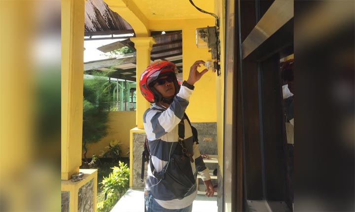 Petugas pencatat meteran memeriksa meteran yang ada di rumah Martin.