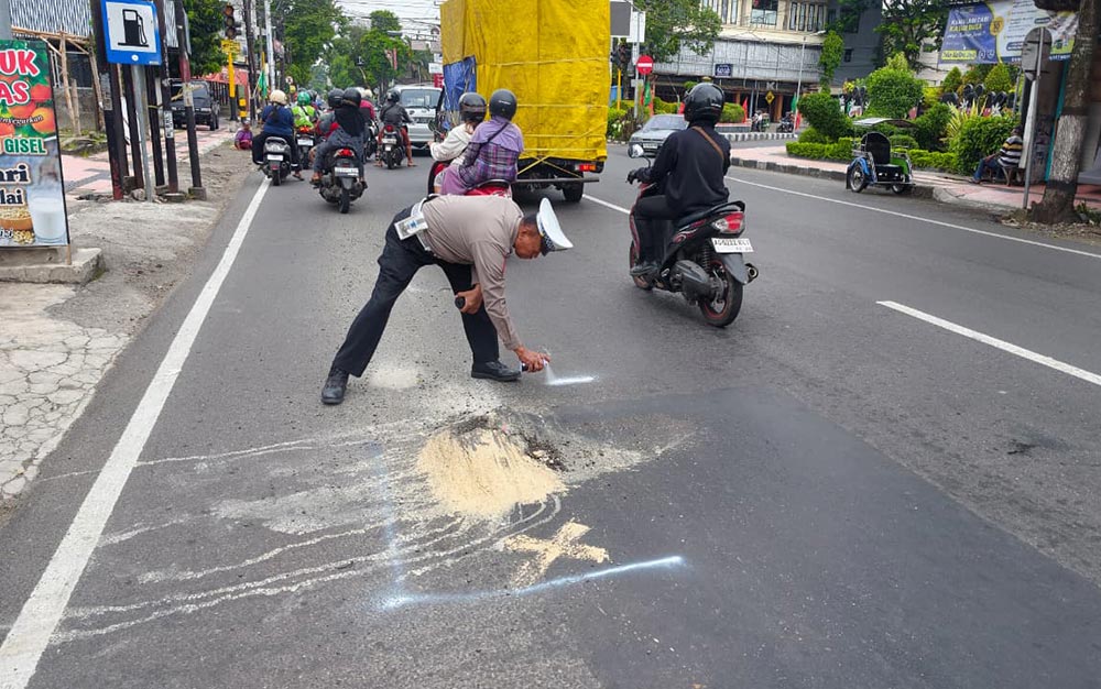 Petugas Satlantas Polres Blitar memberikan penanda pada jalan yang rusak menggunakan cat semprot berwarna putih.